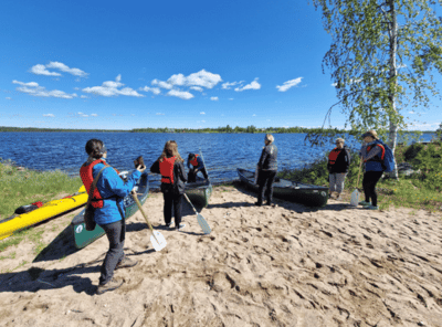 NordicMarketing FAM tripin osallistujat Taivalkosken rannalla lähdässä kanoottiretkelle. 