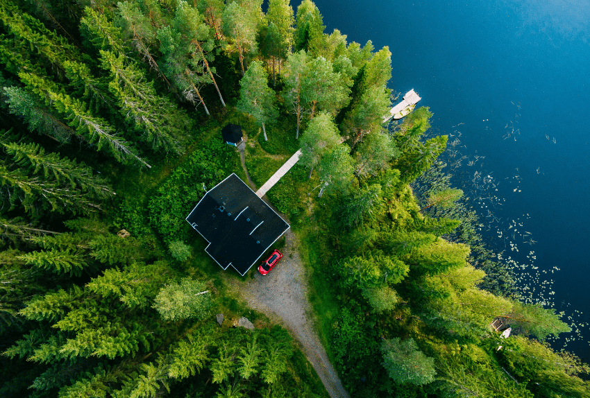Aerial view of wooden cottage in green forest by the blue lake in rural summer Finland@wmaster890 850x574