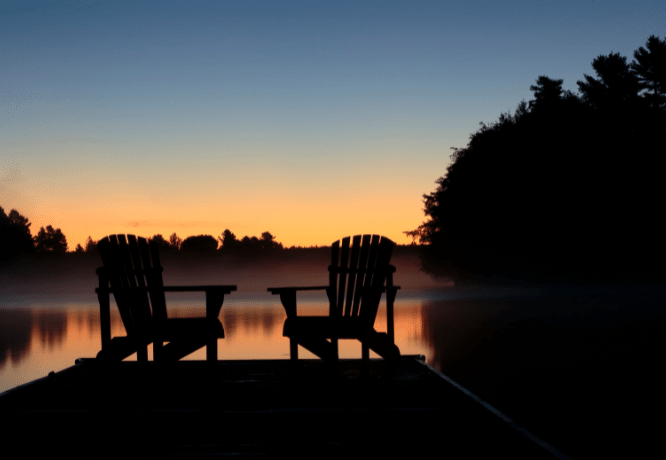 Chairs on the boat dock overlooking the morning mist at the lake. 