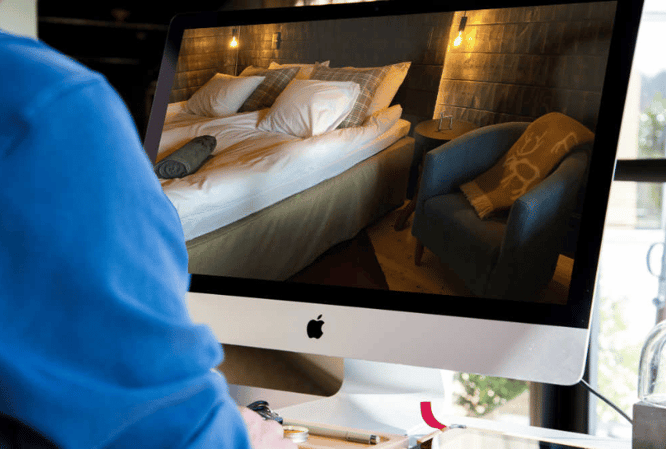 Henkilö tutustuu majoituskohteeseen virtuaalisesti tietokoneen näytöltä. 