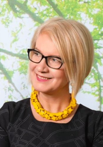 Anu Nylund katsoo kameraan ja hymyilee. 