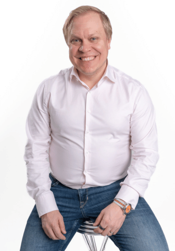 Tuomas Muurinen katsoo kameraan ja hymyilee. 