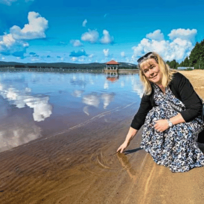 Aija Laukkanen kokeilee tyyntä järven pintaa ja katsoo kameraan. 
