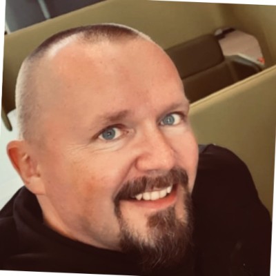 Jukka Vattukallio katsoo kameraan ja hymyilee. 