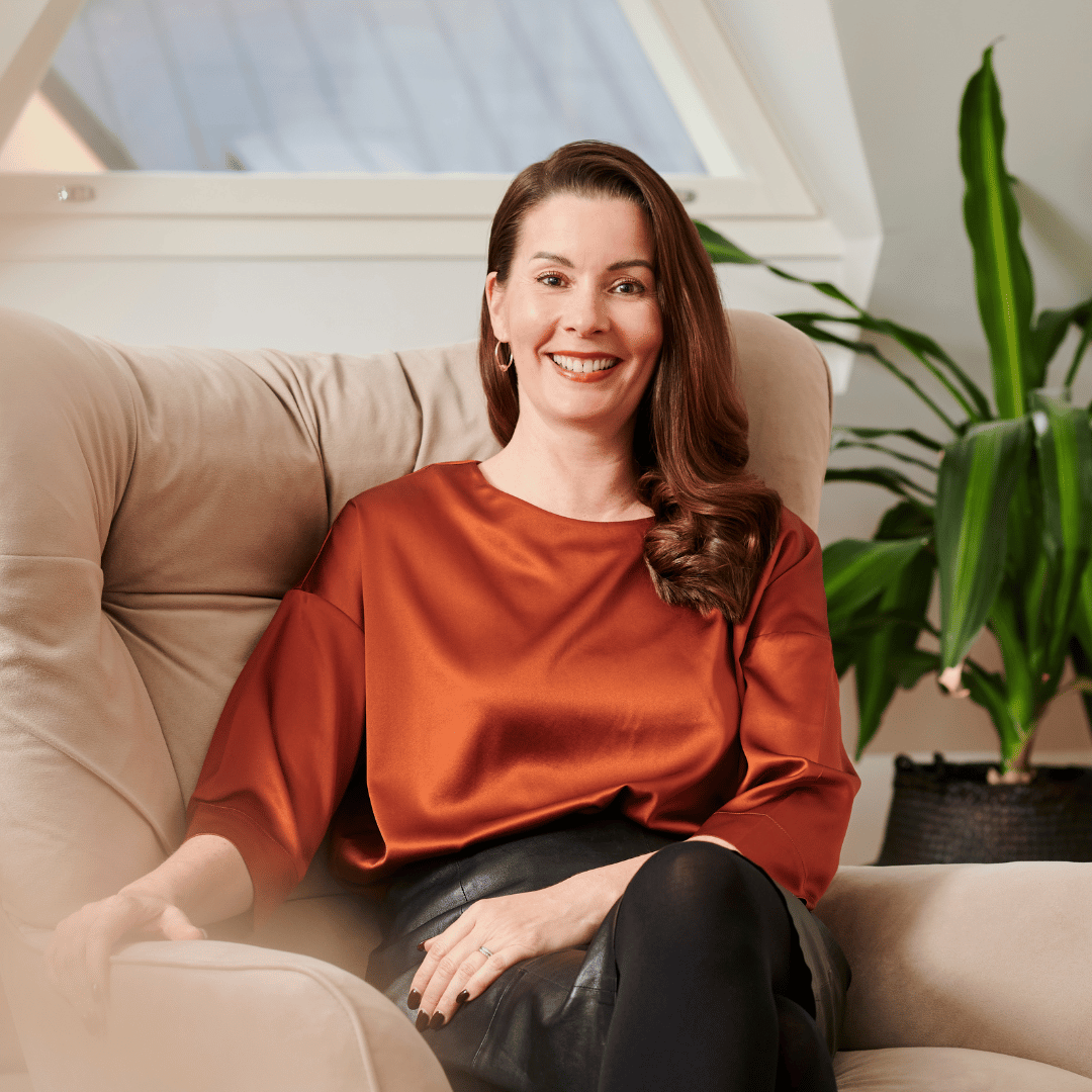 Greta Tanskanen kuvattuna omassa kodissaan ja nauramassa kameraan katsoen. 
